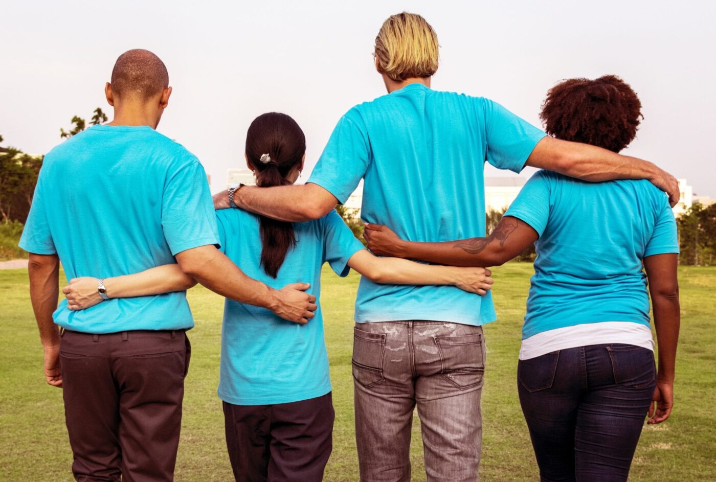 2 men and 2 women arm in arm in a field