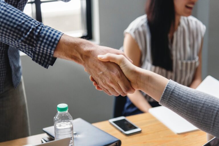 Male shaking a woman's hand across a table