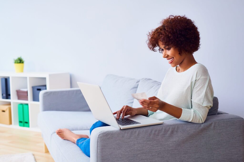 woman on couch with a laptop and credit card