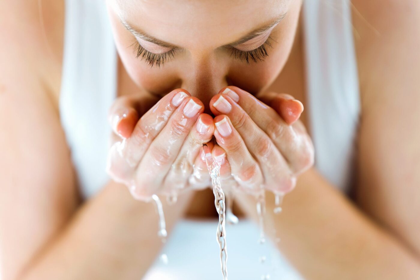 woman with water on hands washing her face