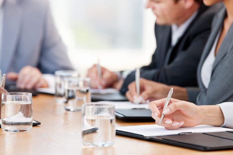group of business men and women with pens in hands