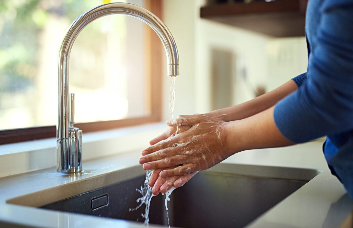 Woman washing her hands in the kitchen sink