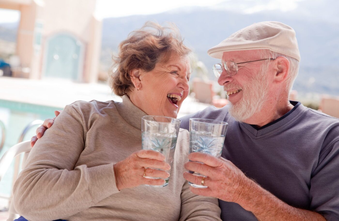 elderly couple smiling and holding glasses of water